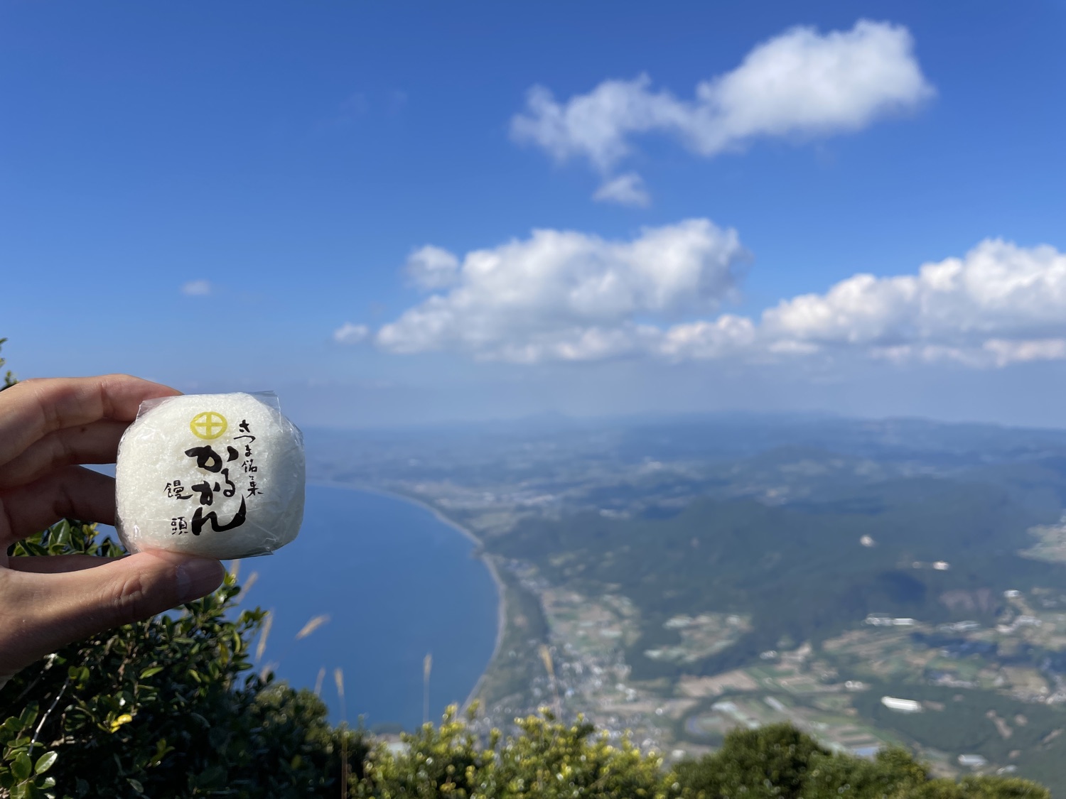 開聞岳の山頂から望む薩摩半島の海岸線と鹿児島銘菓かるかん(筆者撮影)