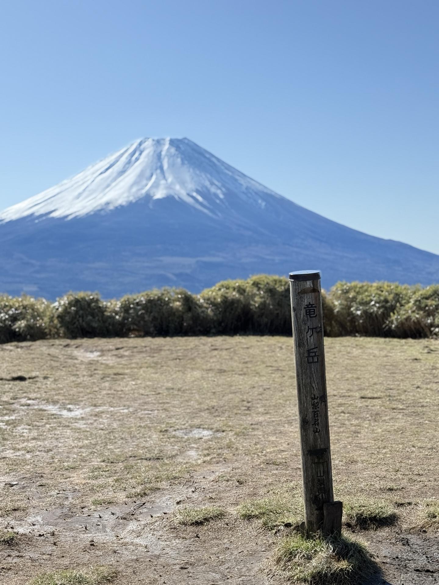 竜ヶ岳の山頂標識と雪化粧の富士山