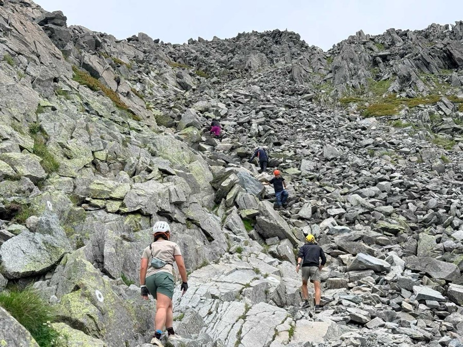 浮石の多いガレ場を登る登山者