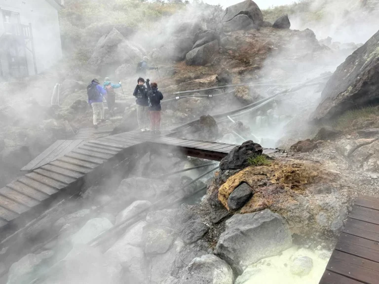 須川高原温泉の横を通る木道と、温泉から上がる湯気